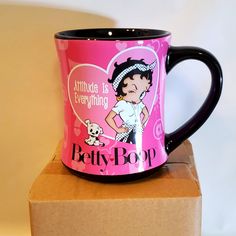 a pink and black coffee mug sitting on top of a cardboard box