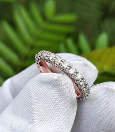 a diamond ring sitting on top of a white cloth next to green plants and leaves