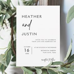 a white wedding card with greenery on it