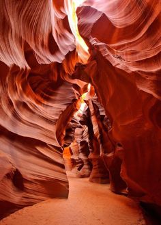 a narrow slot in the side of a canyon with light coming from it's windows