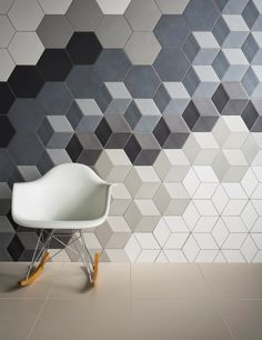 a white chair sitting in front of a wall with geometric tiles on it's sides