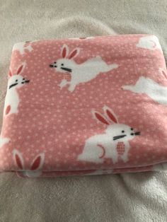 a pink blanket with white rabbits on it and polka dot fabric in the middle, laying on top of a bed