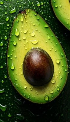 an avocado cut in half with water droplets on the top and one whole