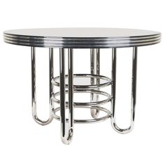 a round glass table with metal bars on the bottom and chrome frame around it, against a white background