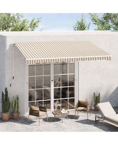 an awning on the outside of a house with patio furniture and potted plants