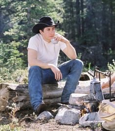 a man sitting on a log drinking from a cup