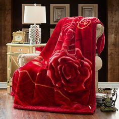 a red rose blanket sitting on top of a wooden floor next to a white chair