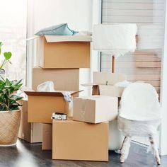 several boxes stacked on top of each other in front of a chair and potted plant