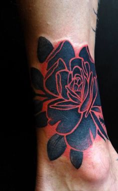 a black and red rose tattoo on the foot