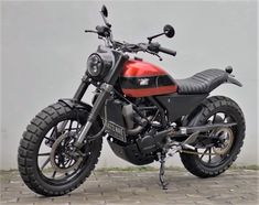 a red and black motorcycle parked in front of a wall