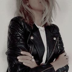 a woman with her arms crossed wearing a black leather jacket