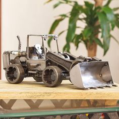 a toy bulldozer sitting on top of a table next to a potted plant