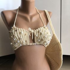 🐚 SEASHELL AND PEARL DETAIL SAND BEIGE CROP BIKINI 🐚 Get ready for an extraordinary beach experience inspired by nature! This handmade crop bikini top is adorned with seashells and pearls, designed in sand beige color. Every detail of this top is meticulously crafted to make you the star of the beach. 🌊 Features and Details: - Handcrafted with natural seashells and pearls. - Sand beige color reflects natural beauty and elegance. - Adjustable straps and ties for a perfect fit. - Long-lasting u Shell Bra Tshirt, Beaded Swimwear For Poolside And Beach Season, Beaded Swimwear For Beach Season, Beaded Triangle Top Swimwear For Vacation, Beige Triangle Halter Top For Beach, Beige Triangle Top Halter For Beach, Summer Beige Halter Top For Beach Season, Summer Beaded Swimwear For Pool, Beaded Swimwear For Beach Festival