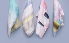 four different colored towels hanging from hooks on a blue wall, with one folded and the other unzipped