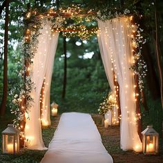 an outdoor wedding ceremony with candles and drapes draped over the aisle, surrounded by greenery