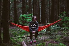 a man sitting on a hammock in the woods