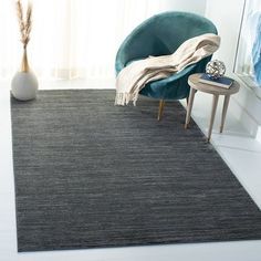 a large rug in the middle of a room with a blue chair and mirror behind it