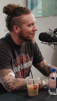 a man sitting at a table in front of a microphone with drinks on the table