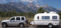 a truck towing a camper with mountains in the background