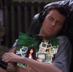 a man sitting in a chair holding up a book with an image of a woman on it