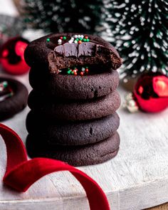 a stack of cookies sitting on top of a wooden table next to a christmas tree