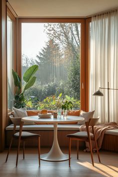 a table and chairs in front of a large window with plants on the windowsill