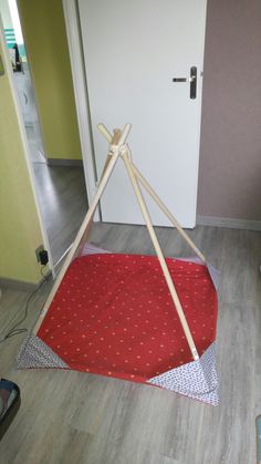 a red and white tent sitting on top of a wooden floor next to a door