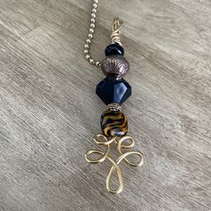 a necklace with two different colored beads hanging from it's side on a wooden surface