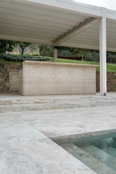 an empty swimming pool in the middle of a patio with stone walls and steps leading up to it