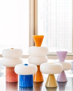 several different colored vases sitting on top of a table next to a large window