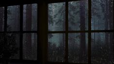 an open window in a dark room with rain falling on the windows and trees outside