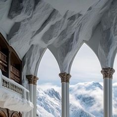 the interior of a building with arches and snow covered mountains in the backgroud