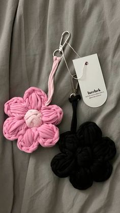 two crocheted flowers are laying on a bed with a tag attached to it