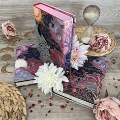 an open book sitting on top of a wooden table next to flowers and other decorations