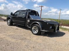 a black truck parked on top of a dirt road