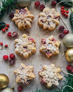 christmas cookies with cranberries and powdered sugar are arranged on a baking sheet