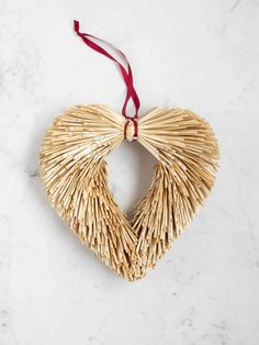 an ornament shaped like a heart made out of straw on a marble surface