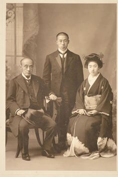 an old black and white photo of two men and a woman in traditional japanese garb