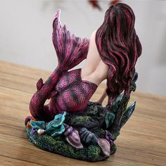 a mermaid figurine sitting on top of a wooden table