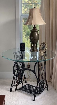 a table with a lamp on top of it in front of a window and curtains