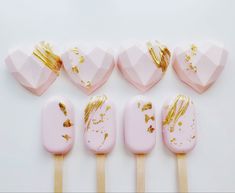 six pink and gold heart shaped lollipops on wooden sticks with golden flakes