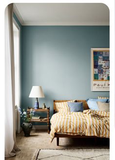 a bed sitting in a bedroom next to a lamp on a wooden floor and a blue wall