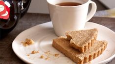 two pieces of bread on a plate next to a cup of tea