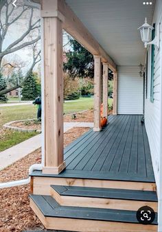 a porch with steps leading up to the front door and an orange pumpkin sitting on top of it