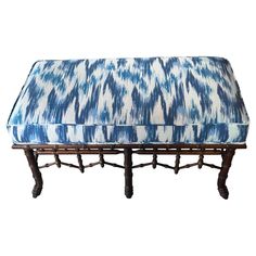 an upholstered bench with blue and white fabric on it's back legs