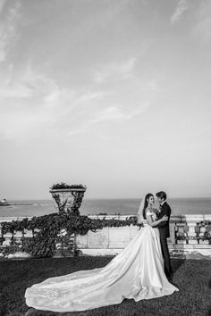 a bride and groom pose for a wedding photo in front of the ocean on their wedding day