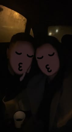 two people with faces drawn on them in the back seat of a car at night