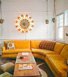 a living room filled with yellow couches next to a coffee table and lamp hanging from the ceiling