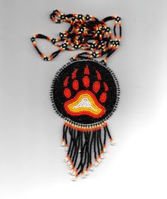 an orange and black beaded necklace with a dog's paw on it