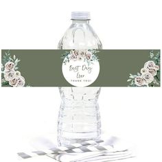 a water bottle label with flowers and greenery on the top, sitting next to silverware